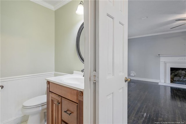 bathroom with ceiling fan, hardwood / wood-style floors, toilet, vanity, and ornamental molding