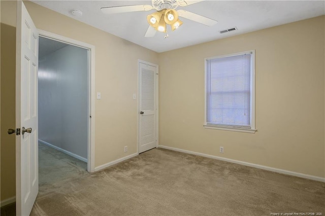 unfurnished bedroom featuring light carpet, a closet, and ceiling fan