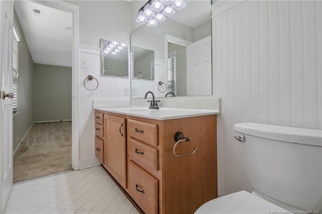 bathroom with vanity, toilet, and wood walls