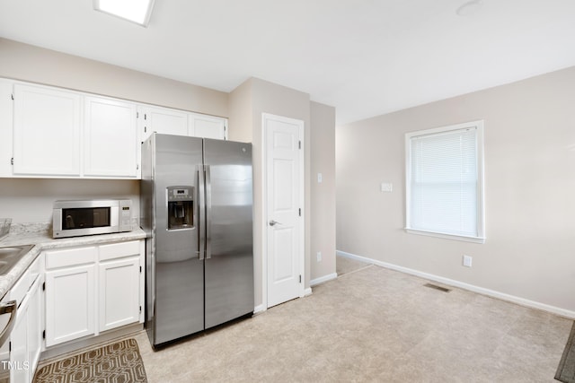 kitchen featuring light colored carpet, white cabinetry, dishwasher, and stainless steel fridge