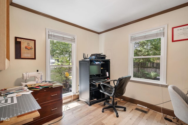 home office featuring a wealth of natural light, ornamental molding, and light wood-type flooring