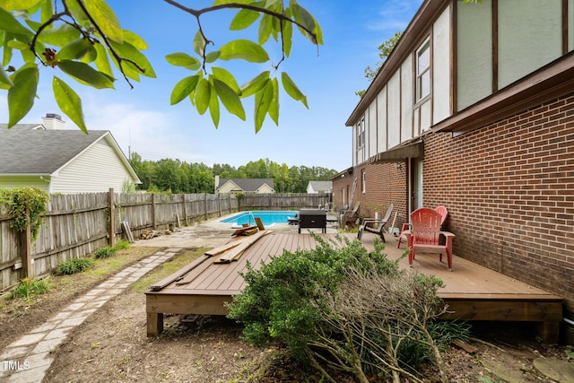 deck with area for grilling and a fenced in pool