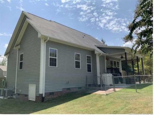 rear view of property featuring ceiling fan, cooling unit, and a lawn