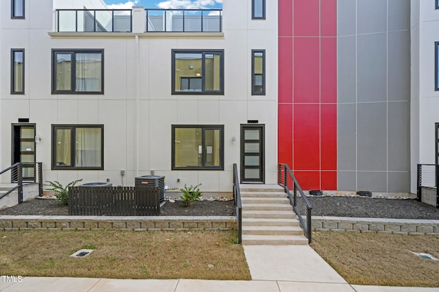 view of front of house featuring a balcony and central air condition unit