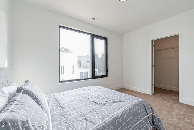 bedroom featuring a spacious closet, a closet, and light colored carpet