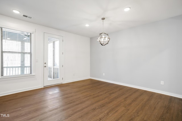 spare room featuring dark hardwood / wood-style flooring and a chandelier