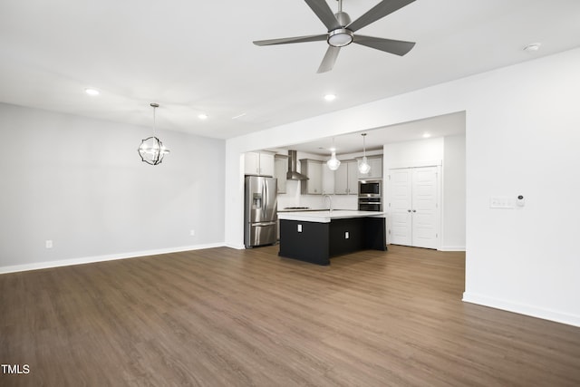 kitchen with stainless steel fridge, a kitchen island with sink, pendant lighting, and wall chimney range hood