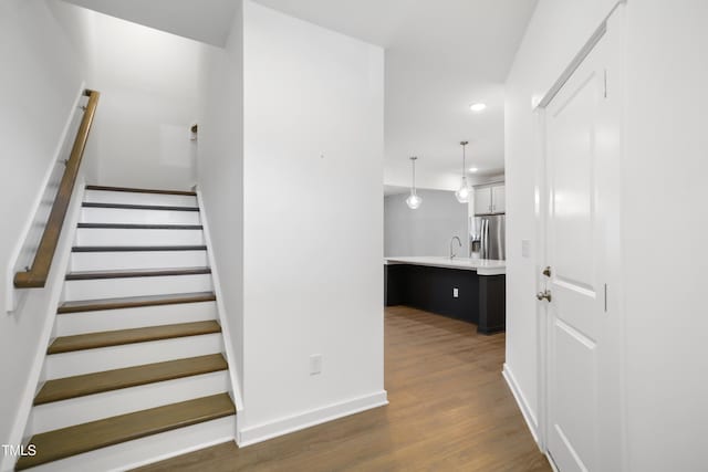 stairs with hardwood / wood-style floors and sink