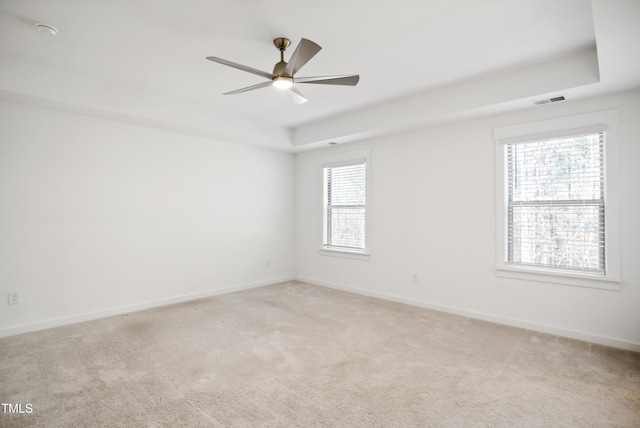 carpeted spare room with a tray ceiling and ceiling fan