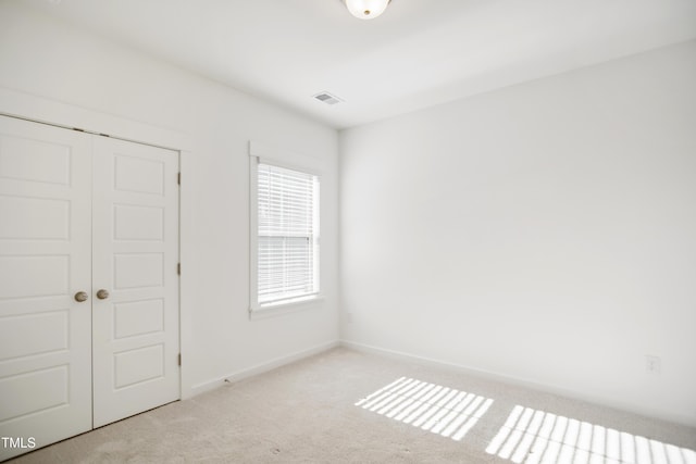 unfurnished bedroom with light colored carpet and a closet