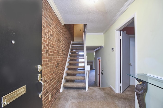 stairway with a textured ceiling, carpet floors, crown molding, and brick wall