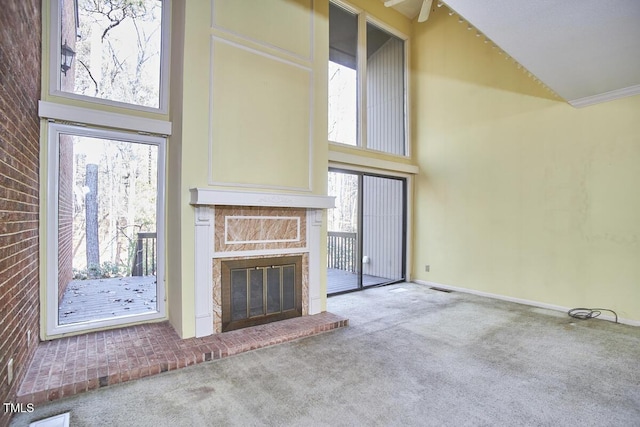 unfurnished living room featuring a fireplace, carpet, a towering ceiling, and plenty of natural light