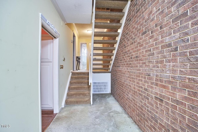 interior space with carpet, brick wall, a textured ceiling, and ornamental molding