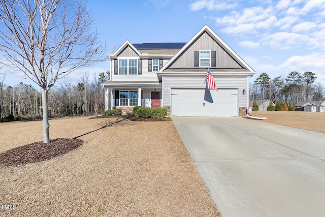 view of front of house featuring covered porch, a garage, and solar panels