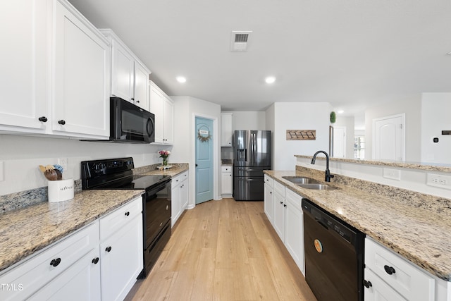 kitchen featuring light stone counters, sink, white cabinets, and black appliances