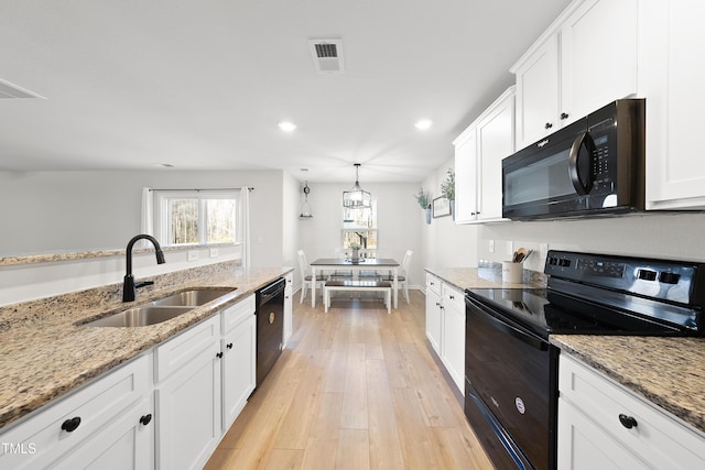 kitchen with pendant lighting, black appliances, sink, light stone countertops, and white cabinets