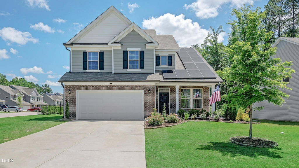 view of front of home with a front yard, solar panels, and a garage