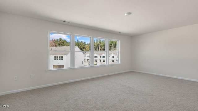 carpeted spare room featuring baseboards and visible vents