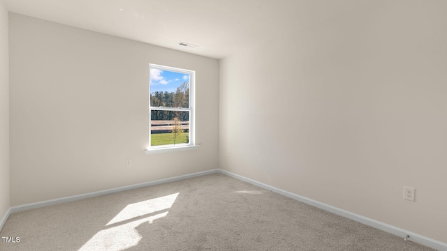 spare room with carpet, visible vents, and baseboards