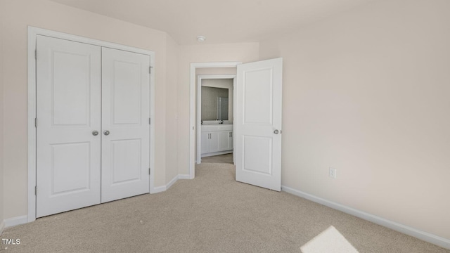 unfurnished bedroom with light carpet, baseboards, and a closet