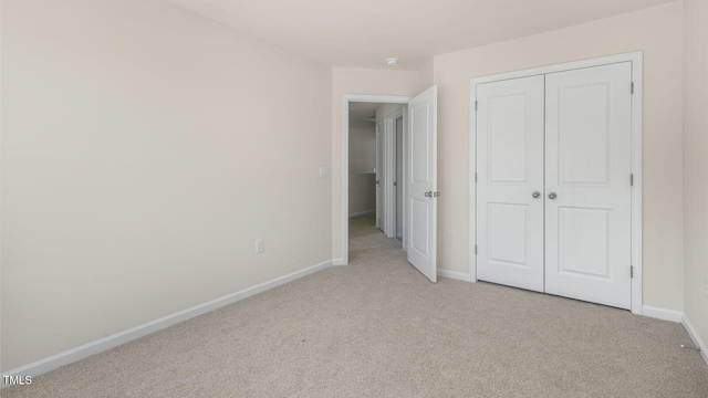 unfurnished bedroom featuring baseboards, a closet, and light colored carpet