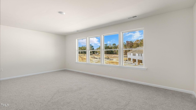 empty room with baseboards, visible vents, and carpet flooring