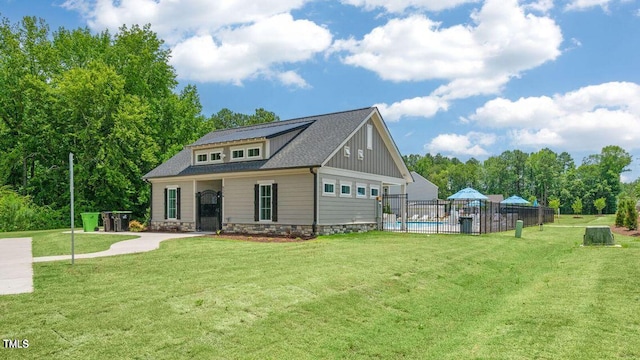 rear view of property featuring a lawn, fence, and a fenced in pool