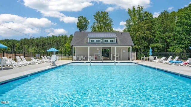 pool with an outbuilding, a patio area, and fence