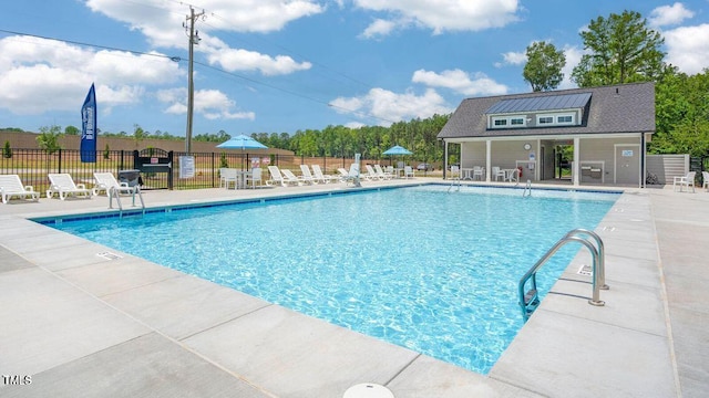 pool with a patio area and fence