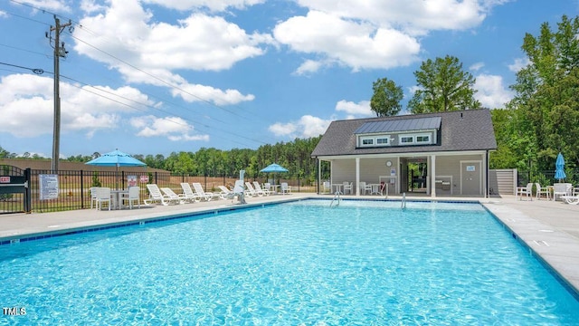 community pool with fence, an outbuilding, and a patio