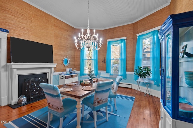 dining room featuring baseboard heating, an inviting chandelier, dark wood-type flooring, and ornamental molding