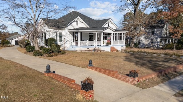 view of front of house with a sunroom, a porch, and a front lawn