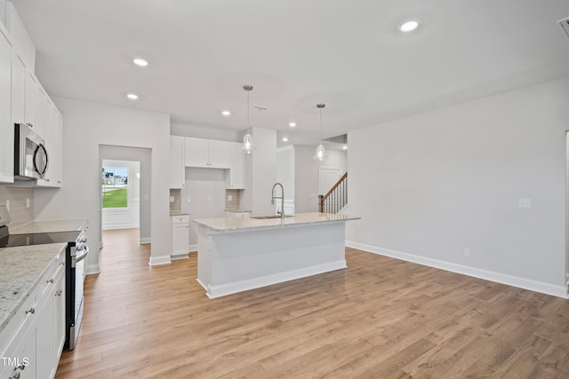 625 Spellbrook Rd, Zebulon, NC 27597 - kitchen with a center island with sink, light wood-style flooring, a sink, appliances with stainless steel finishes, and tasteful backsplash