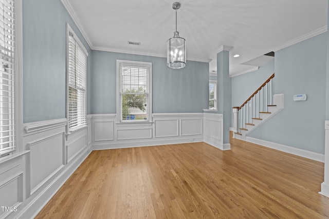 unfurnished dining area featuring light hardwood / wood-style flooring, a chandelier, and ornamental molding