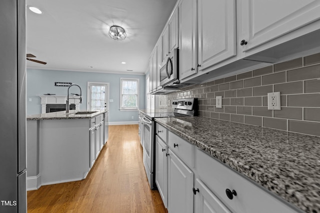 kitchen featuring sink, tasteful backsplash, stone countertops, white cabinets, and appliances with stainless steel finishes