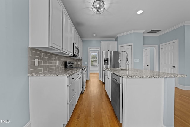 kitchen with sink, appliances with stainless steel finishes, an island with sink, white cabinets, and light wood-type flooring