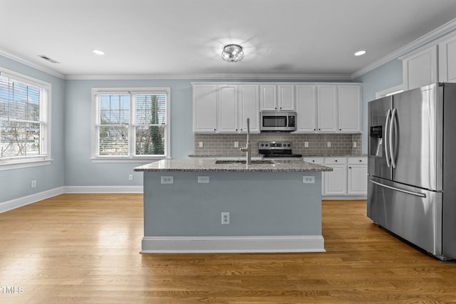 kitchen featuring white cabinetry, a center island with sink, light stone counters, and appliances with stainless steel finishes