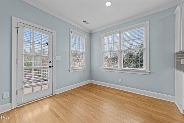 unfurnished dining area with light wood-type flooring and crown molding