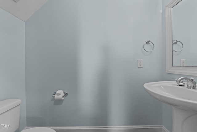 bathroom featuring toilet, sink, and vaulted ceiling