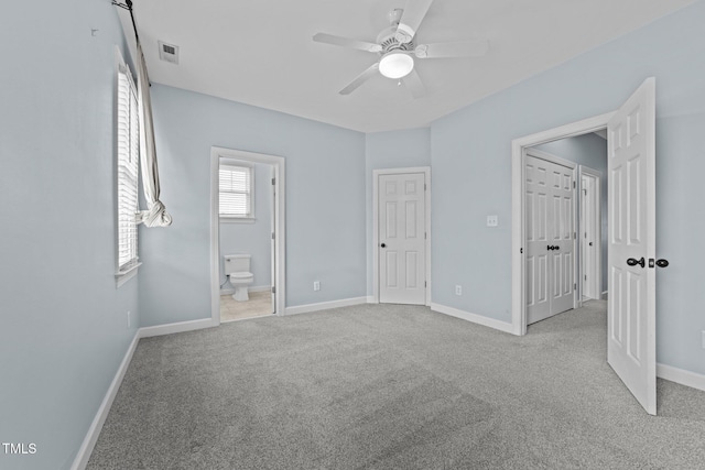 unfurnished bedroom featuring ceiling fan, light carpet, and ensuite bath