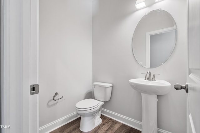 bathroom featuring baseboards, a sink, toilet, and wood finished floors