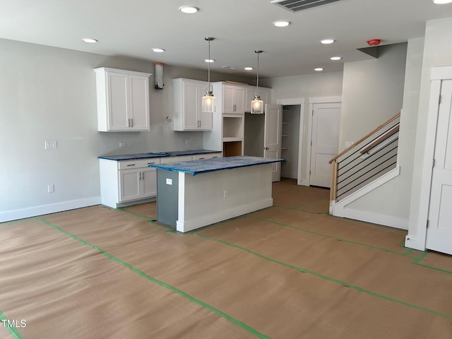 kitchen with hanging light fixtures, a kitchen island, and white cabinets