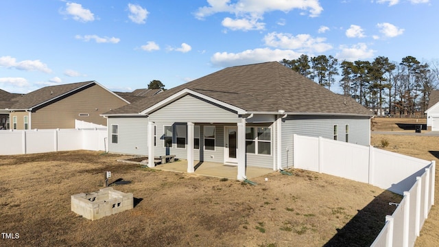 back of property with a fenced backyard, a lawn, a shingled roof, and a patio