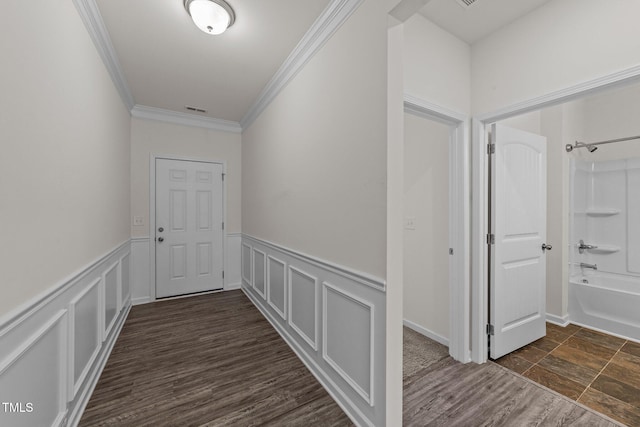 corridor with dark wood-type flooring, a decorative wall, visible vents, and crown molding