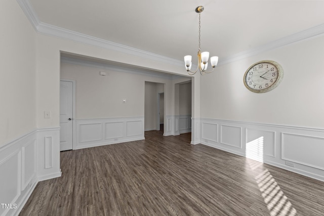 spare room with ornamental molding, dark wood finished floors, and an inviting chandelier