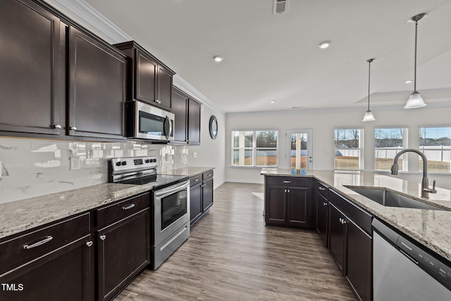 kitchen with sink, appliances with stainless steel finishes, tasteful backsplash, dark brown cabinetry, and decorative light fixtures