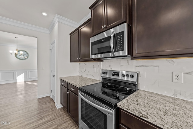 kitchen with stainless steel appliances, crown molding, dark brown cabinets, and light stone counters