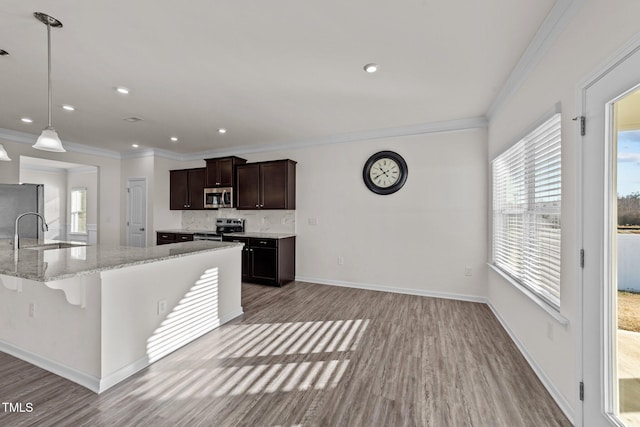 kitchen featuring stainless steel appliances, a sink, baseboards, dark brown cabinets, and decorative backsplash