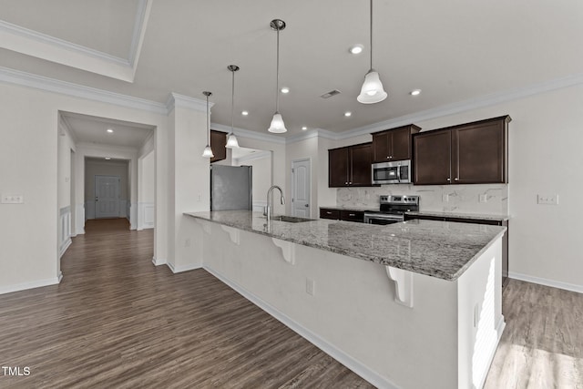 kitchen with sink, light stone counters, a kitchen breakfast bar, pendant lighting, and stainless steel appliances