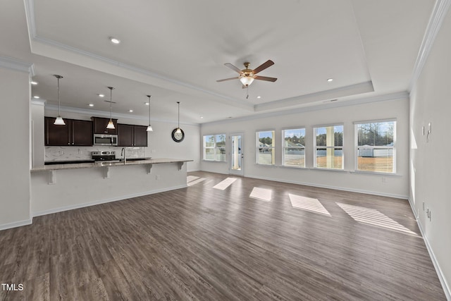 unfurnished living room featuring sink, wood-type flooring, ornamental molding, a raised ceiling, and ceiling fan